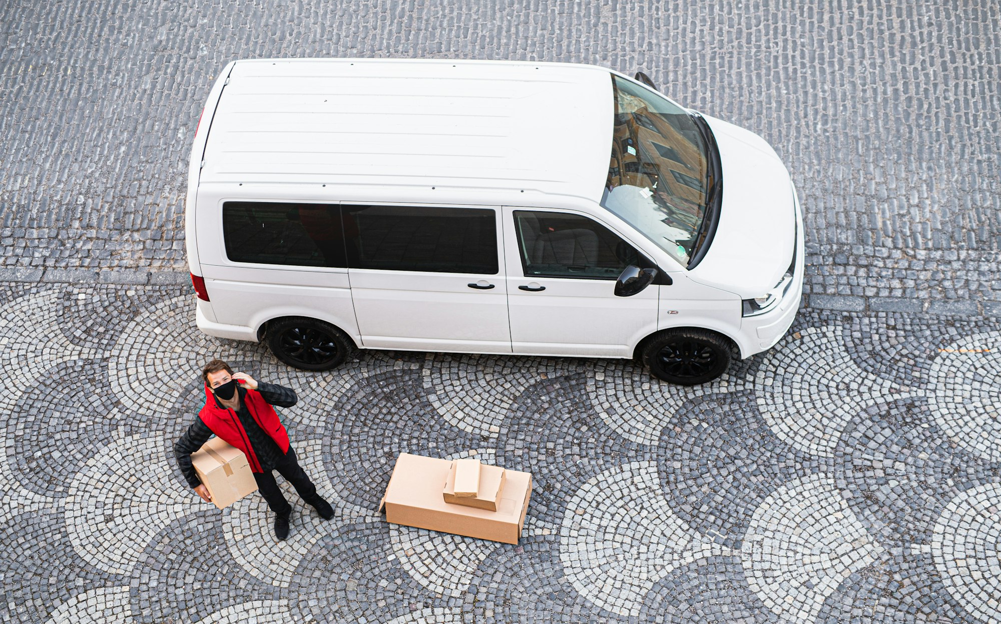 Aerial view of delivery man courier with face mask delivering parcel box in town