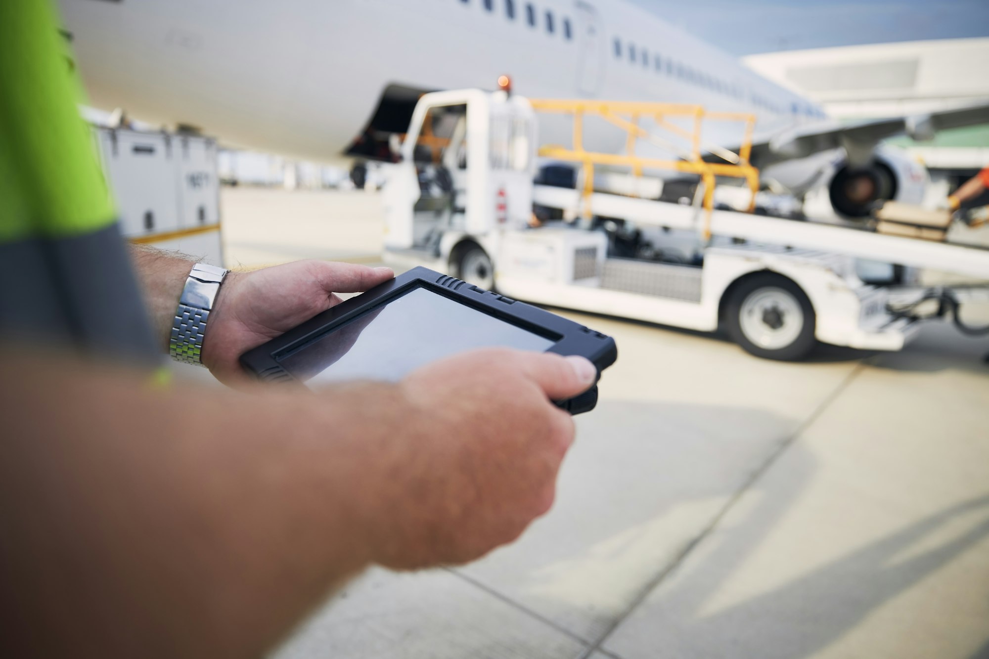 Member of ground staff using tablet against plane at airport